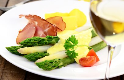 © Der Spargel wird in Karlstadt und Umgebung wie hier im Bild ganz klassisch mit Schinken, Kartoffeln und Sauce Hollandaise serviert, aber auch mit Fisch. Dazu passt jeweils am besten ein fränkischer Silvaner. Foto: djd/Stadt Karlstadt/printemps/Fotolia