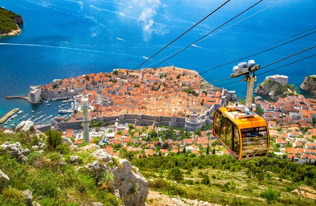Luftpanoramablick auf die Altstadt von Dubrovnik mit der berühmten Seilbahn auf dem Berg Srd an einem sonnigen Tag mit blauem Himmel und Wolken im Sommer, Dalmatien, Kroatien | © ©JFL Photography - stock.adobe.com