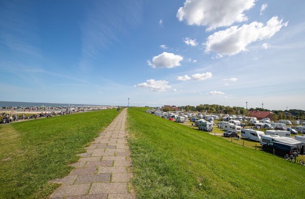 Beim Nordsee-Camping Neuharlingersiel wohnen die Campingurlauber direkt hinterm Deich. | © Foto: djd/TourismusMarketing Niedersachsen/Martin Stoever