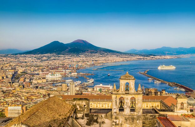 Ansichtskartenansicht der Stadt Napoli (Neapel) mit dem berühmten Vesuv im Hintergrund im goldenen Abendlicht bei Sonnenuntergang, Kampanien, Italien | © ©JFL Photography - stock.adobe.com